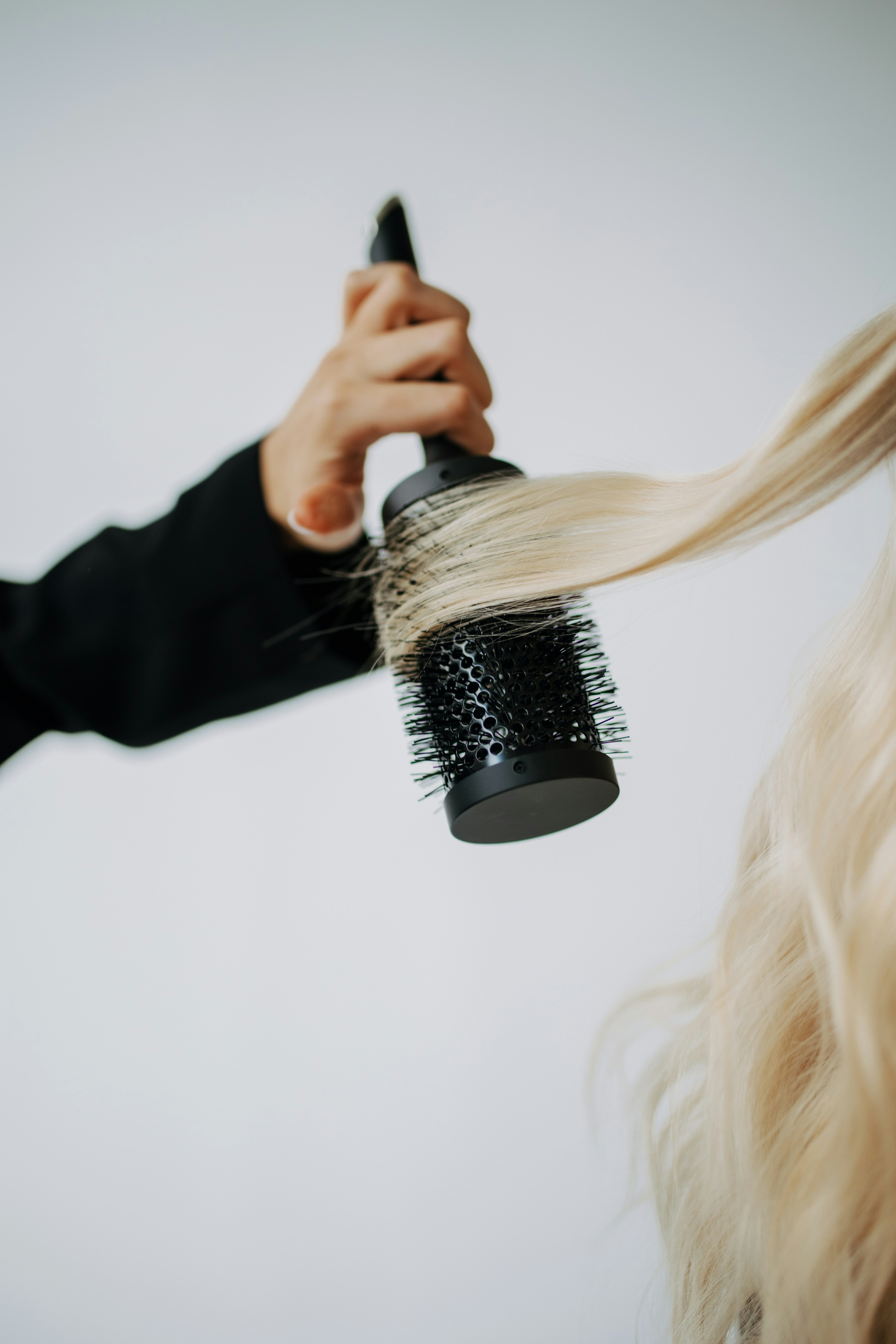 Stylist blow-drying and prepping hair with a round brush